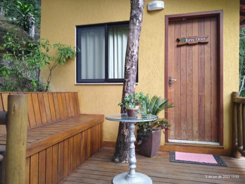 a porch with a table and a door and a tree at Espaço Viverde Penedo in Penedo