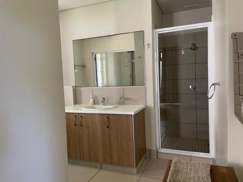 a bathroom with a sink and a shower with a mirror at The Herolds Bay 611 in Herolds Bay