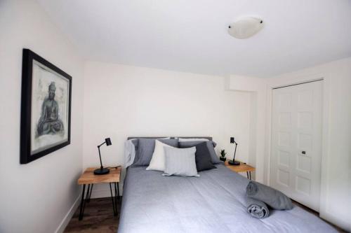 a white bedroom with a bed with two tables at Confo28 Chute Montmorency Parking in Quebec City
