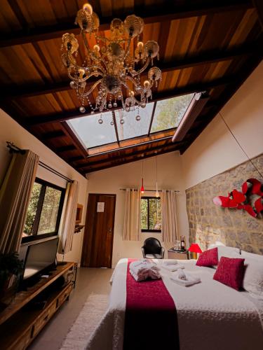 a bedroom with a large bed and a chandelier at Espaço Viverde Penedo in Penedo