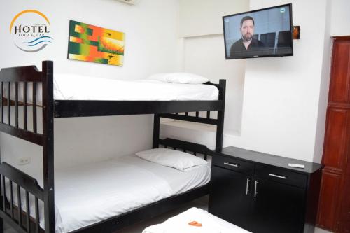 a room with two bunk beds and a flat screen tv at Hotel Roca & Mar in Santa Marta