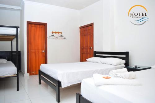 a room with three beds and a sign that reads hotel at Hotel Roca & Mar in Santa Marta