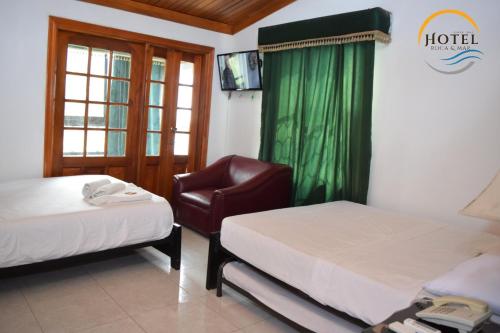 a hotel room with two beds and a chair at Hotel Roca & Mar in Santa Marta
