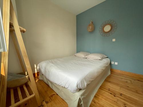 een kleine slaapkamer met een bed en een houten vloer bij La Glycine in Mers-les-Bains