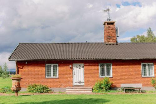 una casa di mattoni rossi con camino e porta bianca di Bonäs bygdegård a Mora