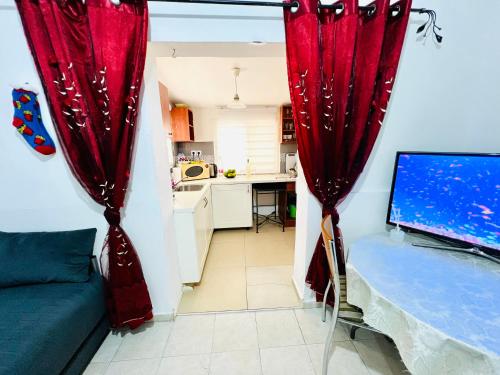 a living room with red curtains and a kitchen at КВАРТИРА ВОЗЛЕ МОРЯ! in Haifa