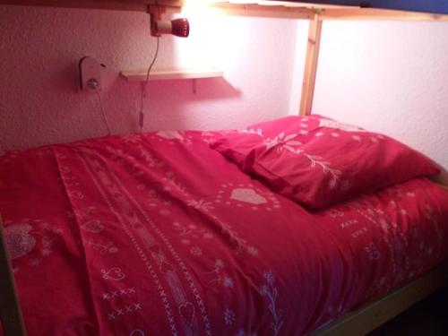 - un lit avec une couette rouge dans une chambre dans l'établissement Studio 4 couchages 