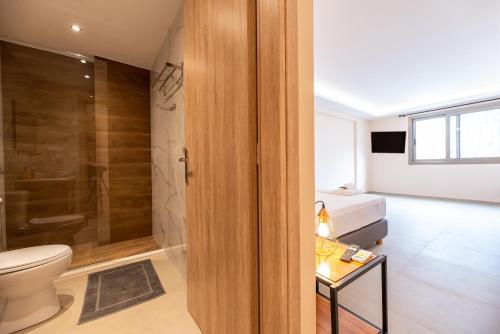 a bathroom with a shower and a toilet and a bed at Mini Suites Free shuttle from and to Athen's Airport in Spáta