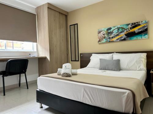a bedroom with a large bed with a chair at Laureles Guest House LGH Hotel in Medellín
