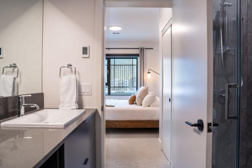 een badkamer met een wastafel en een bed in een kamer bij Altitude Adjustment by Revelstoke Vacations in Revelstoke