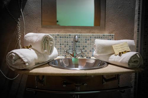 a bathroom sink with towels and a mirror at Hostal Bavieca in Medinaceli