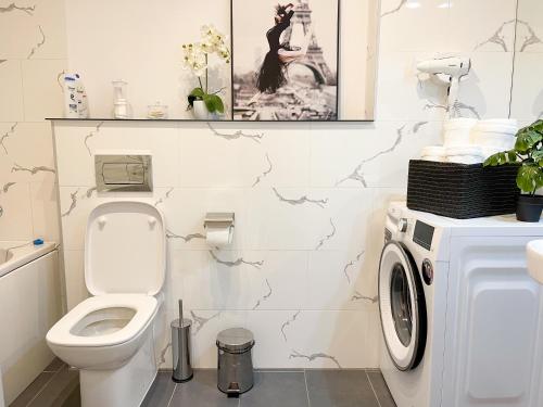 a bathroom with a toilet and a washing machine at Emerald Apartment in Arad