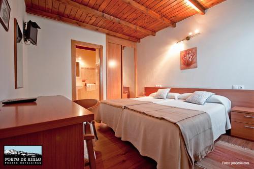 a bedroom with two beds and a desk and a sink at Porto de Rinlo in Rinlo
