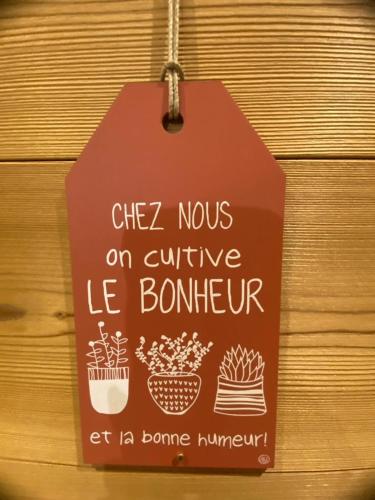 a sign hanging on a wooden wall with some plants at Appartement Cosy centre station in Vénosc