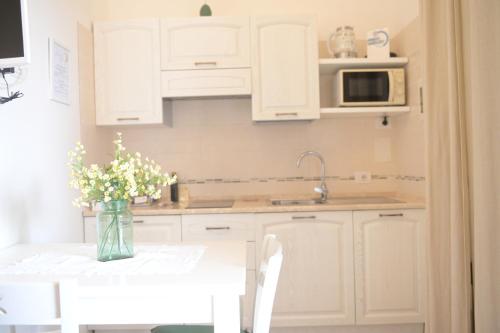 a kitchen with white cabinets and a table with flowers at BdL Open Space in Marsala