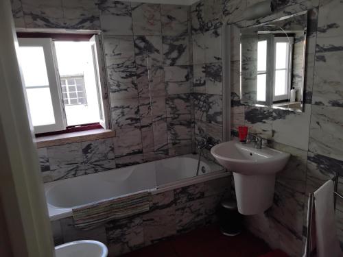 a bathroom with a sink and a tub and a toilet and a mirror at Great duplex in historical center in Lisbon