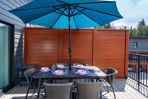 a table with a blue umbrella on a deck at Peak Paradise by Revelstoke Vacations in Revelstoke