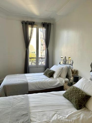 two beds in a room with a window at appartement in Vitry-sur-Seine