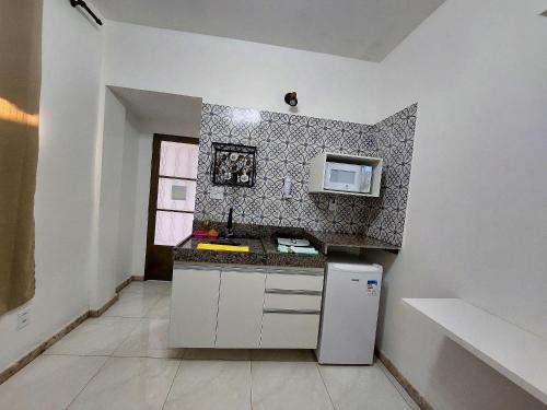 a small kitchen with a refrigerator and a microwave at Confortáveis e práticas Kitnets em Belo Horizonte in Venda Nova