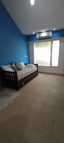 ein Schlafzimmer mit einem Bett in einer blauen Wand in der Unterkunft Jugueze Tres Arroyos No tiene cochera in Tres Arroyos