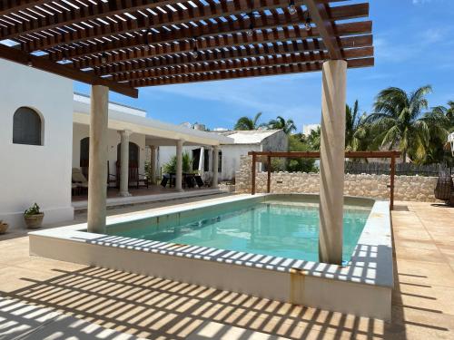 a swimming pool in a house with a wooden pergola at Casa familiar, alberca privada, pasos de la playa in Progreso