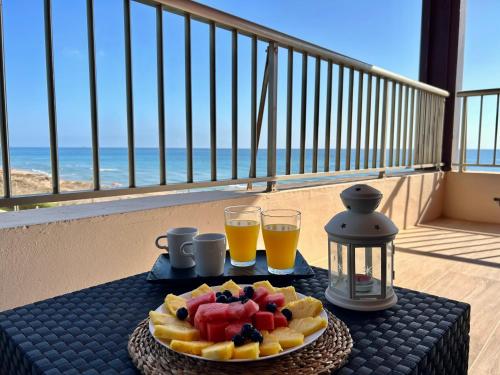 een tafel met een schaal fruit en twee glazen sinaasappelsap bij Mareny de Barraquetes in Mareny Blau