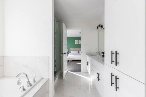 a white bathroom with a tub and a sink at Comfortable Lux, Sleeps 10, PingPong, Movie Room in London
