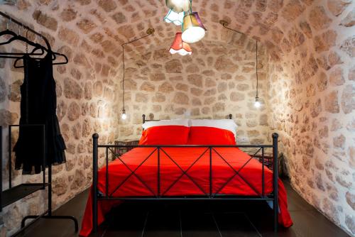 a bedroom with a red bed in a brick wall at Guest House La Bohème in Dubrovnik