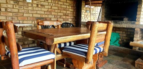 einen Holztisch und Stühle in einem Zimmer mit Ziegelwand in der Unterkunft VillaMed Guesthouse in Klerksdorp