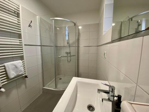 a white bathroom with a shower and a sink at M&F Apartman in Egerszalók