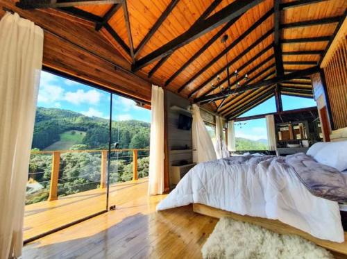 - une chambre avec un grand lit et une grande fenêtre dans l'établissement Chalé Canto da Montanha, à Annitapolis