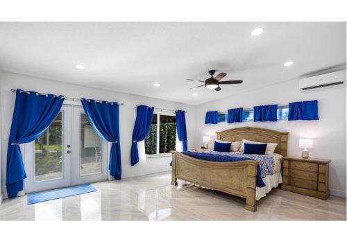 1 dormitorio con cortinas azules y 1 cama con ventilador de techo en Casa de Cox, Home w/heated pool, en Southwest Ranches