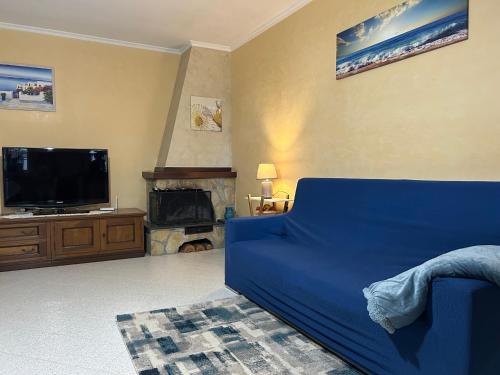 a living room with a blue couch and a tv at Demetra Apartment Sperlonga in Sperlonga