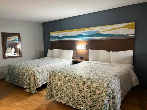 a hotel room with two beds and a painting on the wall at HomeTowne Studios by Red Roof Amarillo West in Amarillo