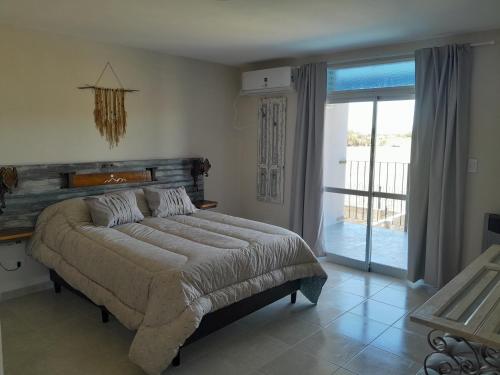 Schlafzimmer mit einem Bett und einer Glasschiebetür in der Unterkunft Apart Fincas de San Pablo in Deán Funes