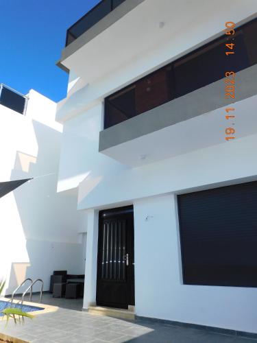 a white building with a black door at Villa avec Piscine Privée. in Saidia 