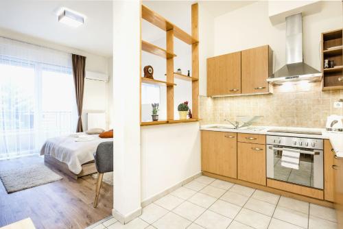 una cocina con armarios de madera y una cama en una habitación en Downtown charm with balcony and garden view, en Budapest