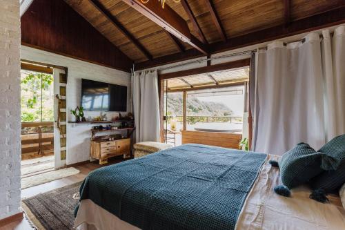 1 dormitorio con cama y ventana grande en Ondas da Grande Spa Cama e Café, Praia Grande, Penha, Santa Catarina, en Penha