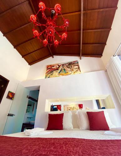 a bedroom with a red bed with a chandelier at Espaço Viverde Penedo in Penedo