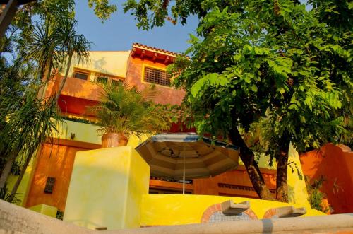 an umbrella in front of a building with trees at Quinta del Encanto in Cruz de Huanacaxtle