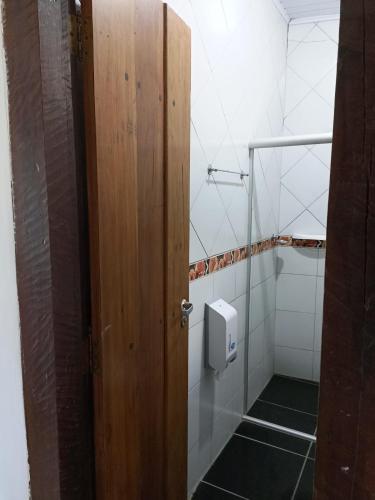 a bathroom with a wooden door and a urinal at Pousada Portal da Mucugê in Porto Seguro