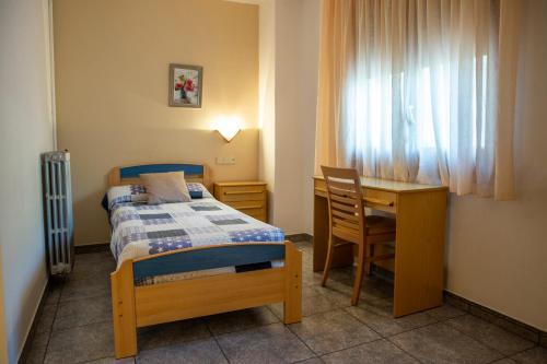 a bedroom with a bed and a desk and a table at Hostal Montserrat in Montseny