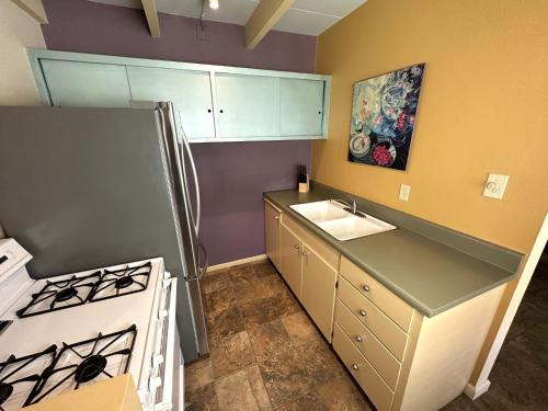 a small kitchen with a stove and a sink at Vista Grande Resort - A Gay Men's Resort in Palm Springs