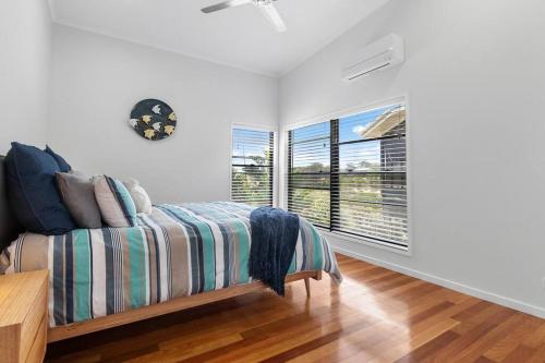 a white room with a bed and two windows at Allure Beach House - Formerly Sands on Moreton in Tangalooma
