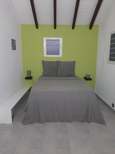 een bed in een kamer met een groene muur bij Zaboka delair in Sainte-Anne