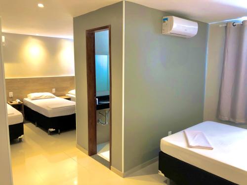 a small room with two beds and a mirror at Mega Aeroporto Hotel Apenas 1 km de distância do Aeroporto de Fortaleza in Fortaleza