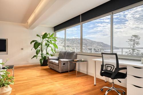 an office with a desk and chair and large windows at Jasmineiro, a Home in Madeira in Funchal
