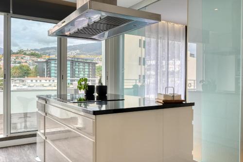 a kitchen with a counter top with a large window at Jasmineiro, a Home in Madeira in Funchal