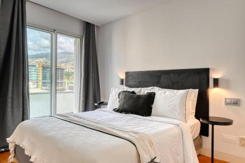 a bedroom with a large bed with a large window at Jasmineiro, a Home in Madeira in Funchal