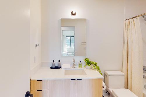 a white bathroom with a sink and a mirror at Life of the Party, Unit #418 in Nashville